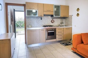 A compact kitchen with wooden cabinets, a built-in oven, and a sink. - M329 -  Marcelli, one bedroom apartment with garden and garage (Marcelli)