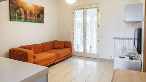 Un salon avec un canapé, un tableau, un téléviseur et un radiateur.