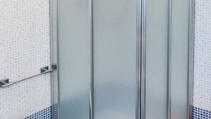 Une salle de bain avec une douche à parois de verre, un porte-serviettes et un carrelage décoratif.