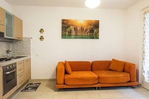 A modern kitchen with a built-in oven and a dining area with a sofa.