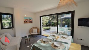A dining area with a table set for four, a wicker chair, and a sofa with a cushion marked '4'. - Hossegor “VILLA BARRANX” Magnificent apartment for 4 people. (HOSSEGOR)