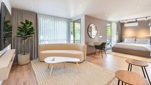Ein modernes Schlafzimmer mit einem Bett, einer Couch, einem Schreibtisch und einem großen Spiegel.