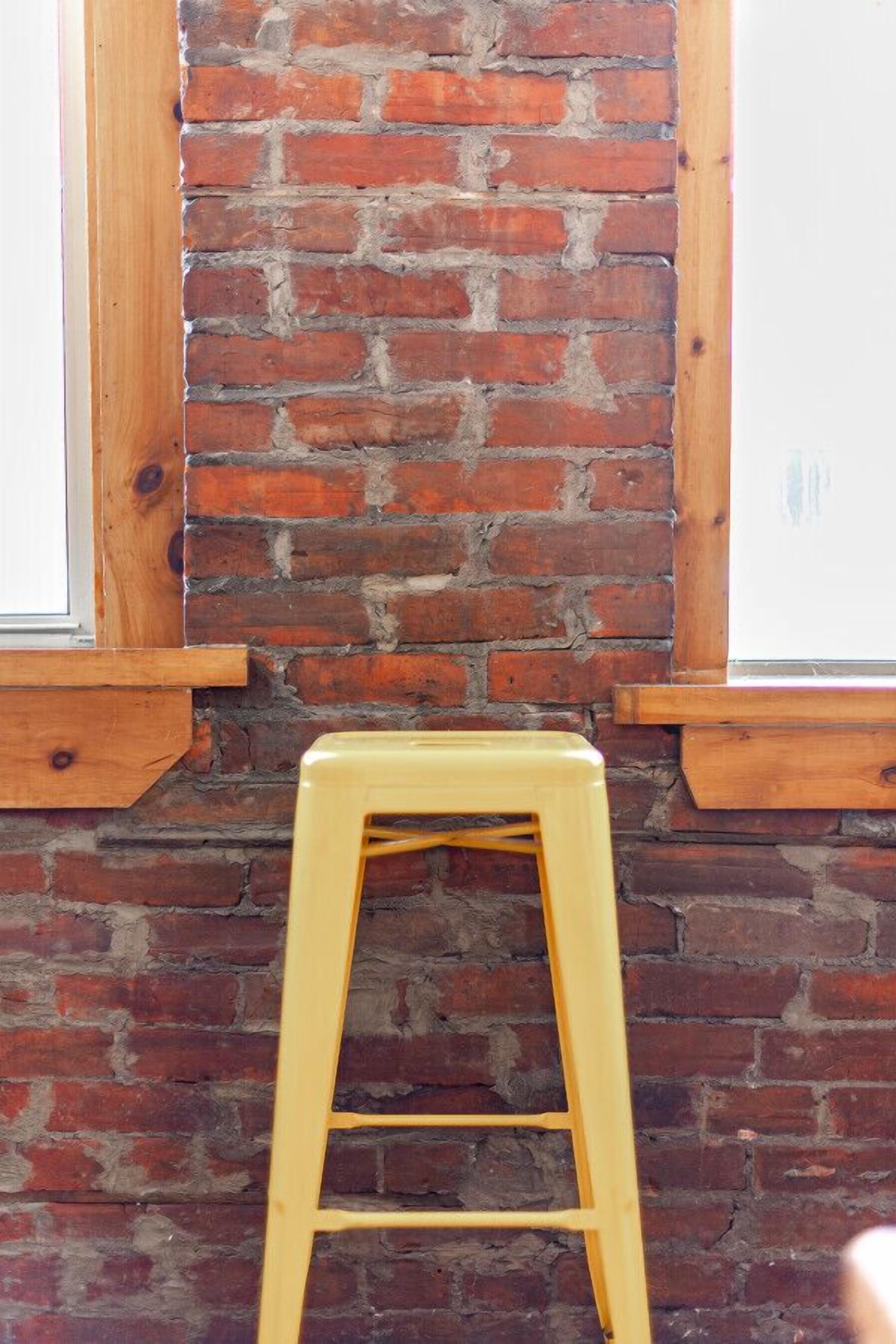 A brick wall with a wooden ladder leaning against it.