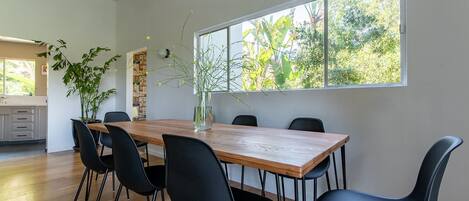 A dining area with a wooden table, black chairs, and a vase with flowers.