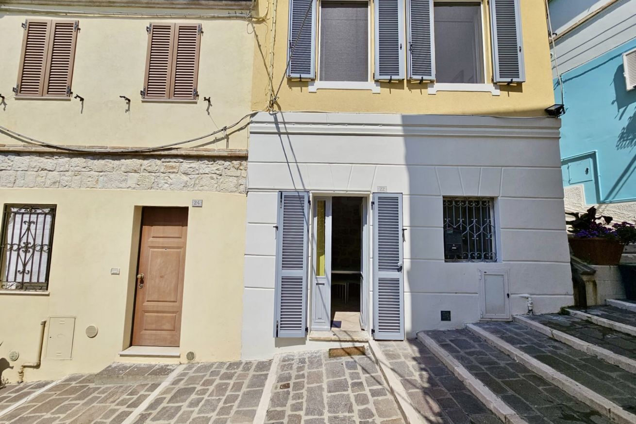 Una stretta via con edifici dalle facciate in pietra e persiane.