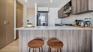 A modern kitchen with a central island, wooden cabinets, and a stainless steel refrigerator. - Fesh, Modern,Panoramic View, Close to El Tesoro! (Medellín)