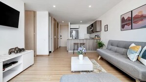 A modern living room with a grey sofa, a white coffee table with a vase, and a TV mounted on the wall. - Fesh, Modern,Panoramic View, Close to El Tesoro! (Medellín)
