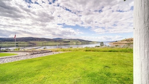 A grassy area with a river and hills in the background. - Seven Bays Vacation Rental on Lake Roosevelt! (Seven Bays)