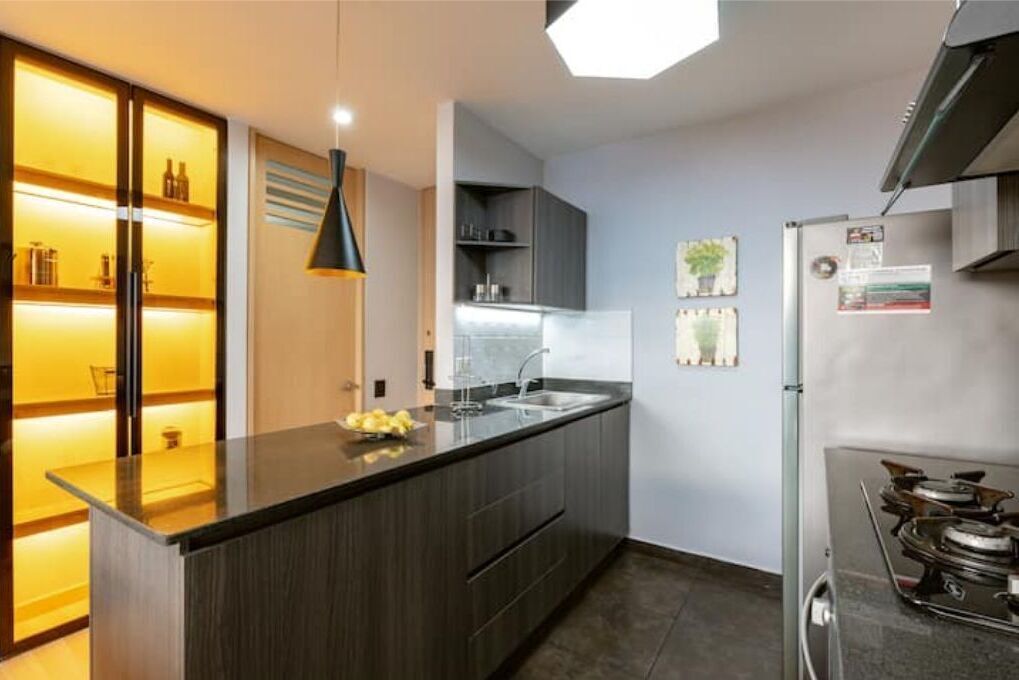 Una cucina moderna con isola in legno scuro, forno integrato e frigorifero in acciaio inossidabile.