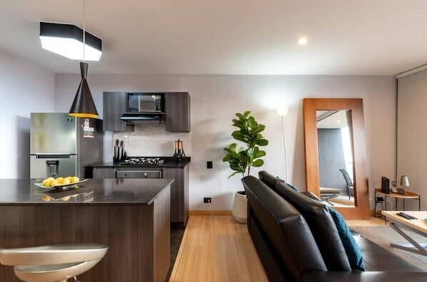A modern kitchen with dark cabinetry, a central island, and a pendant light.