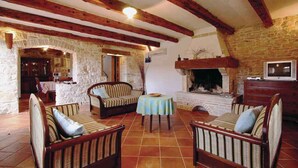 Un interior rústico con vigas de madera a la vista, paredes de piedra, chimenea y un comedor.