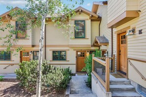 A multi-story residential building with a front porch, a mailbox, and a small garden area.