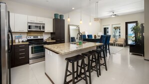 Una cocina moderna con electrodomésticos de acero inoxidable, una encimera de granito y una isla central con taburetes de bar.
