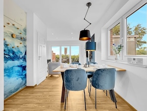 A modern dining area with a wooden table, blue chairs, and a pendant light. - 50124 Delft berth - pure peace and quiet and a view! - You have earned this: - (Wittmund)