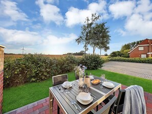 An outdoor dining area with a table set for four, surrounded by a well-maintained garden and a brick wall. - 50124 Delft berth - pure peace and quiet and a view! - You have earned this: - (Wittmund)