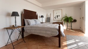 A bedroom with a wooden bed, two bedside tables with lamps, a large window, and a framed artwork on the wall. - ITS A Room IN A Shared House (Caldas da Rainha)