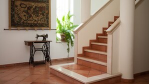 A staircase with a white handrail and a wooden banister, leading to a landing with a sewing machine and a large tapestry on the wall. - ITS A Room IN A Shared House (Caldas da Rainha)