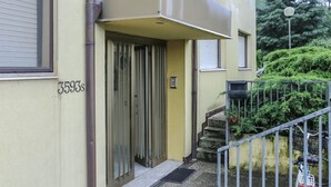 Un bâtiment à la façade jaune, doté d’un portail en métal et d’un escalier menant à une porte.