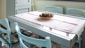 Une table à manger avec un saladier rempli de nourriture, des chaises bleu clair et un buffet dans une pièce avec une fenêtre.