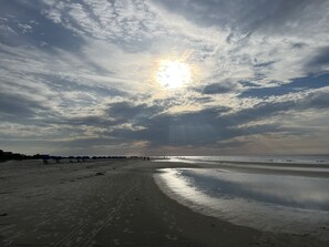 Una playa con cielo despejado, sol y agua tranquila.