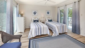 A bedroom with two beds, a ceiling fan, and a view to the outside. - Stones throw from shore!  Spacious multi-level townhome one row back from beach (St. Simons Island)