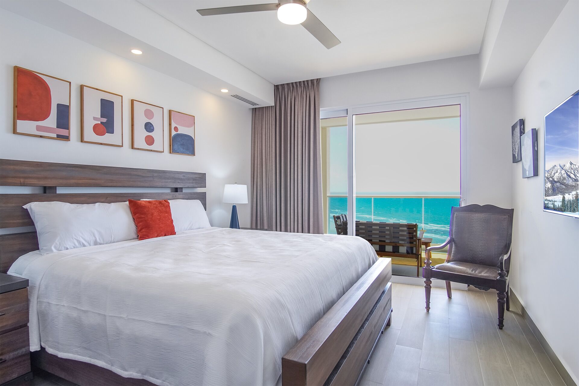 Habitación de hotel con una cama grande, una silla, vista al océano y obras de arte en la pared.