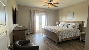 Un dormitorio con cama, una silla, un escritorio y un ventilador de techo.