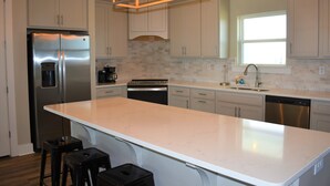 Una cocina moderna con una isla grande, electrodomésticos de acero inoxidable y un salpicadero de estilo rústico.