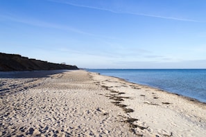 A sandy beach with a clear sky and calm sea.