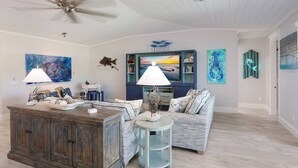 A spacious living room with a wooden coffee table, a blue sofa, and a ceiling fan.