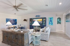 A spacious living room with a wooden coffee table, a blue sofa, and a ceiling fan.