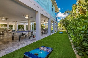 An outdoor area with a ping pong table, seating, and a covered section with tables and chairs.