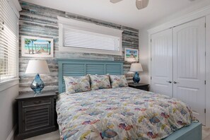 A bedroom with a bed, two nightstands, a window with blinds, and a door. - Manatee Lookout: Canal Front, Pool, Spa, Dock, Putting Green by Anna Maria Life Vacation Rentals (Anna Maria)