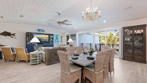 A spacious living room with a dining area, large windows, and a ceiling fan.
