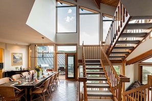A dining area with a long table, chairs, and a view of the outdoors. - Prime Location, Private Hot Tub & Wi-Fi + Free Shuttle! (Park City)