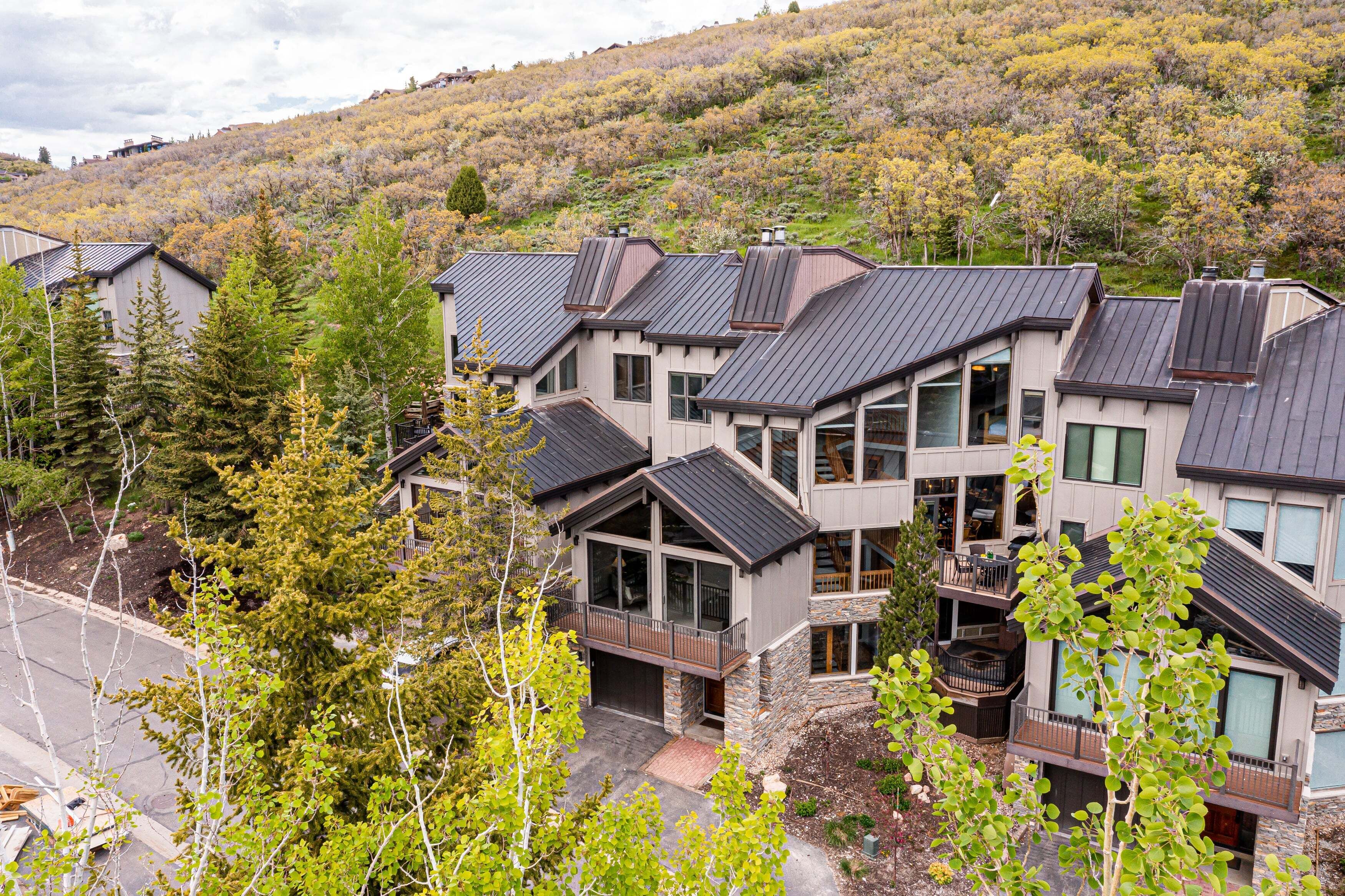 A modern multi-story residential building with a stone facade, large windows, and a balcony.