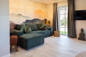 A living room with a sofa, ottoman, and a Buddha statue.