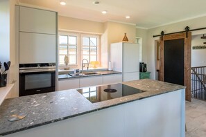A modern kitchen with a central island, built-in oven, and a large window providing natural light.