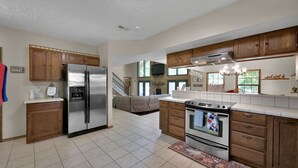 A spacious kitchen with wooden cabinets, a stainless steel refrigerator, and an oven. - Texas History Vacation House (Houston) (San Jacinto County)