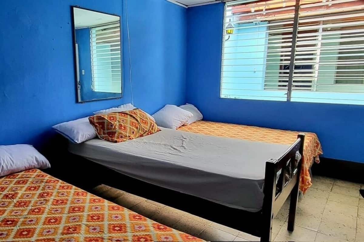 Ein Zimmer mit zwei Betten, blauen Wänden und einem Fenster mit Jalousien.
