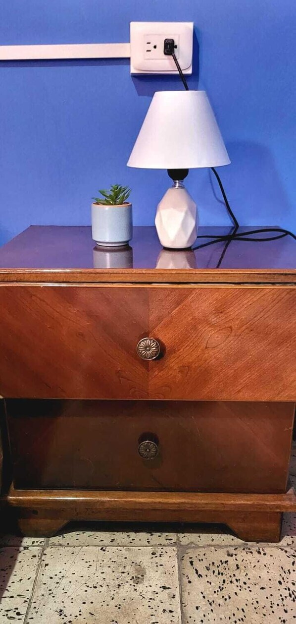 A wooden dresser with a white lamp and a small potted plant on top. - Hostal Cisne House (León)