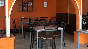 A dining area with tables and chairs, an archway, and a wall with framed pictures. - Hostal Cisne House (León)