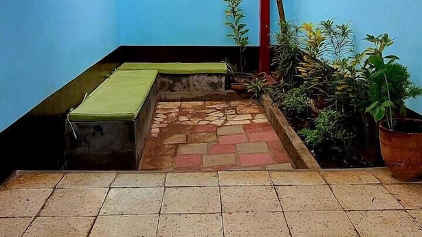 A courtyard with a tiled floor, a bench, and a wall with a sign. - Hostal Cisne House (León)