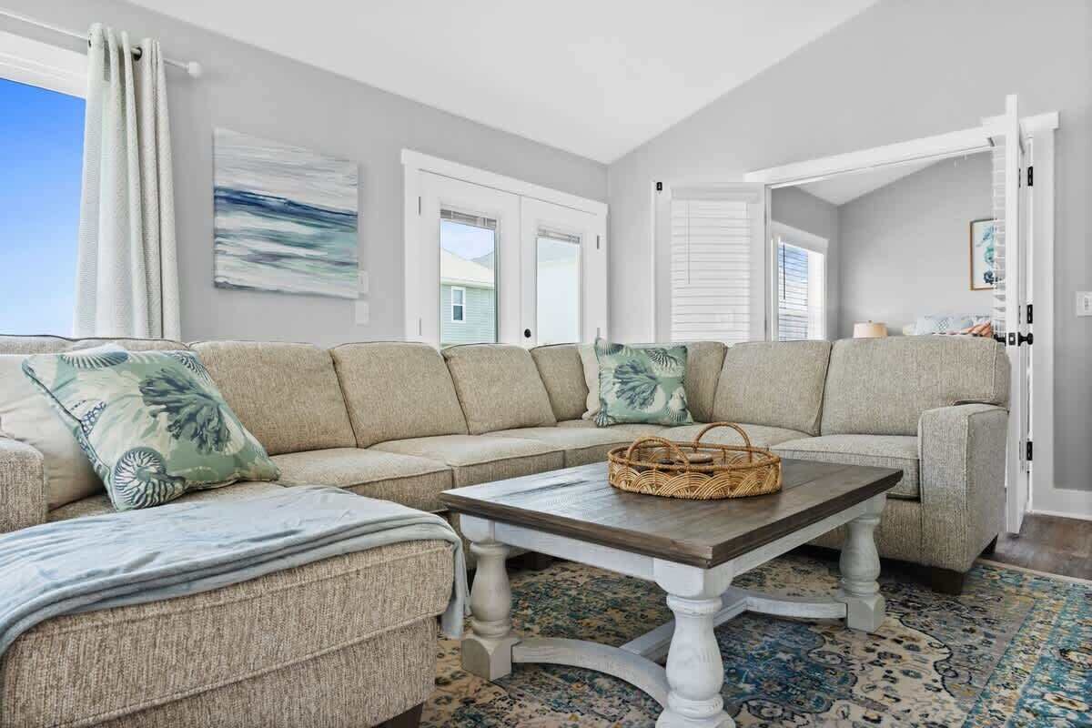 A living room with a sectional sofa, a coffee table, and a patterned rug.