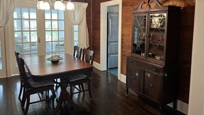 Un comedor con mesa de madera, sillas y una alacena con puertas de vidrio.