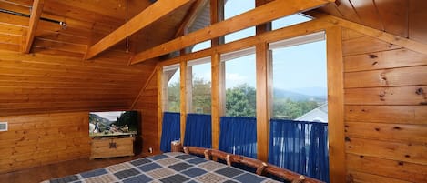 Relax in this cabin with a large bed, wooden dresser, and television, surrounded by a scenic view.