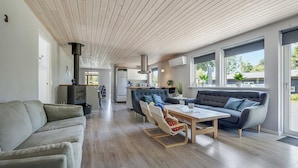 A modern living room with a sofa, a dining table, and a kitchen area in the background.
