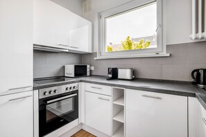 Een koelkast, een magnetron, een oven, kookgerei, borden en bestek