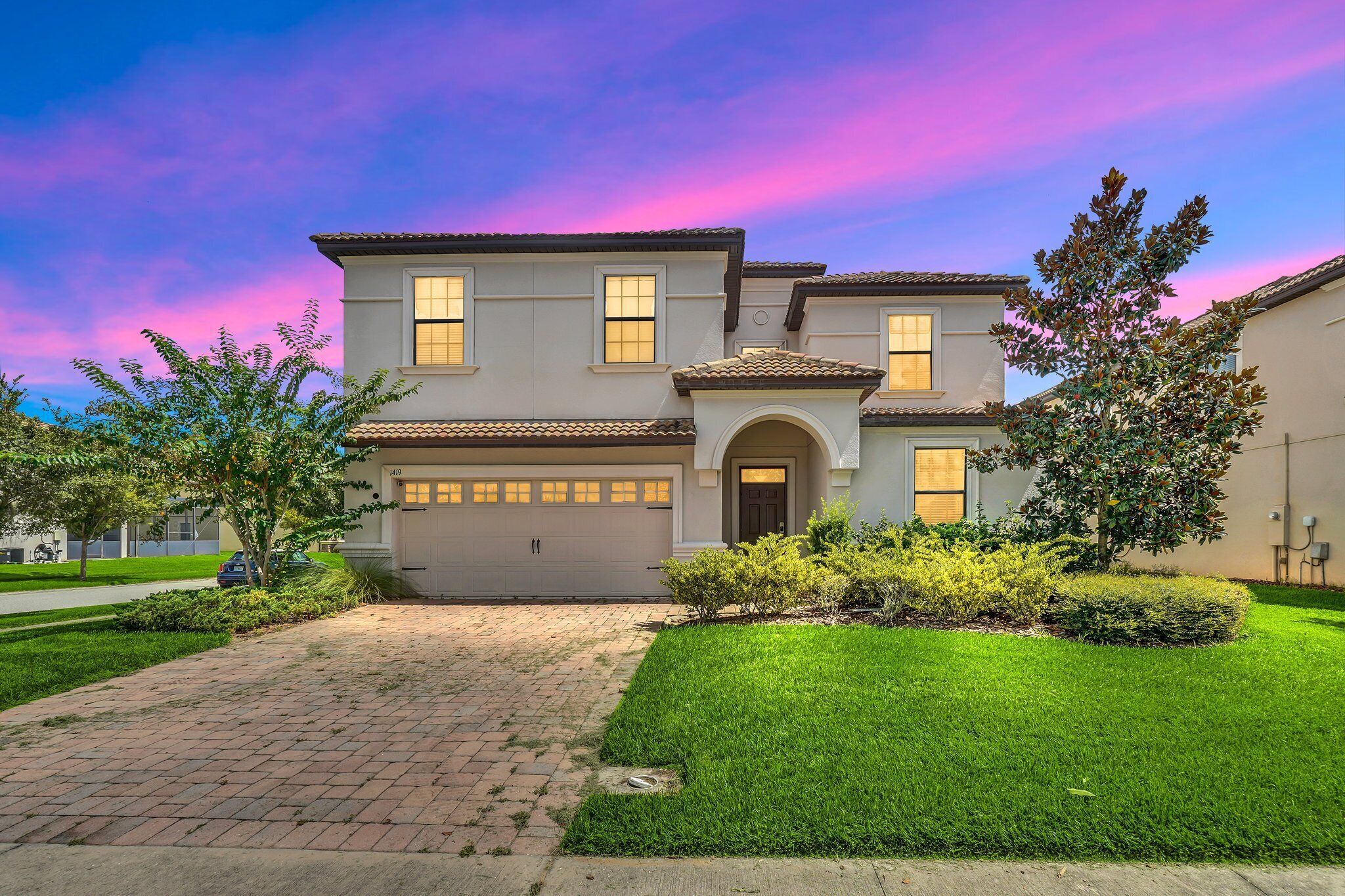 A two-story house with a driveway, garage, and well-maintained lawn.
