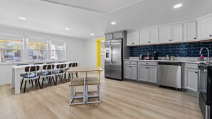 Una cocina moderna con armarios blancos, electrodomésticos de acero inoxidable y un comedor con mesa y sillas.